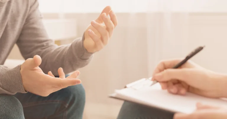 Counsellor taking notes while a client talks during a therapy session