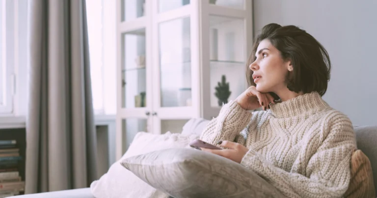 Woman sitting thoughtfully at home while considering therapy support